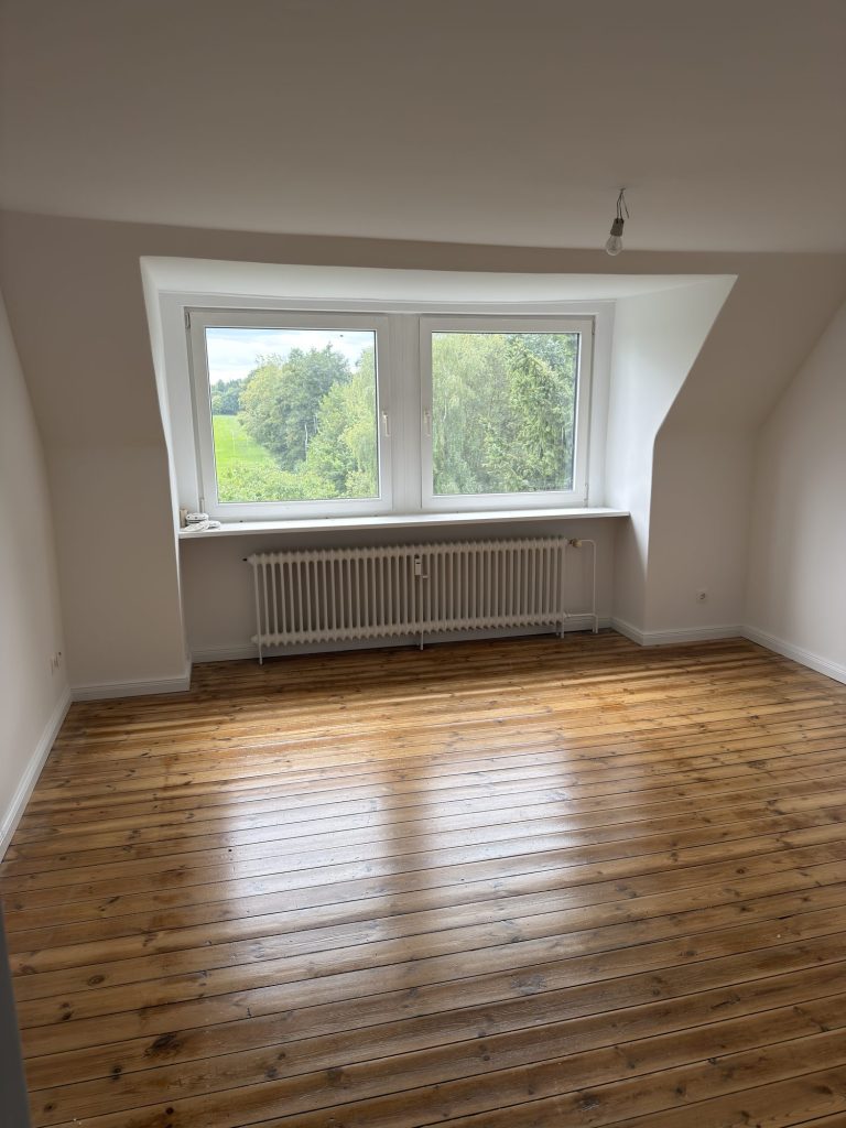 Zimmer mit Gaubenfenster, Holzdielen und Blick ins Grüne